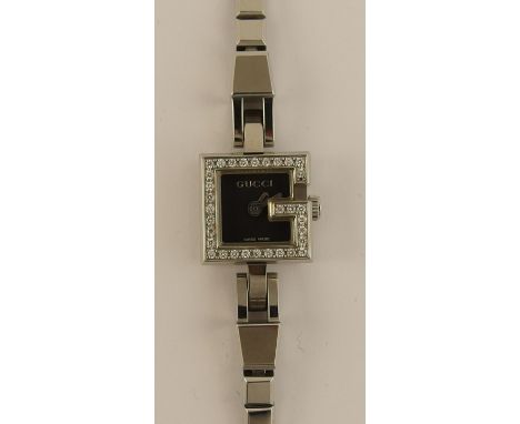 A ladies 'G' Gucci watch with a black dial silver coloured baton hands and a diamond set bezel, in stainless steel head size 