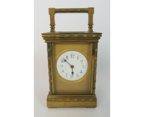 A French brass carriage clock the blue and white dial set within a gilt engine turned face, the case cast with faux bamboo mo