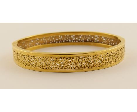 A French 18ct pierced scrollwork bangle with further engraved decoration, the French eagle hallmark is stamped to the tongue 