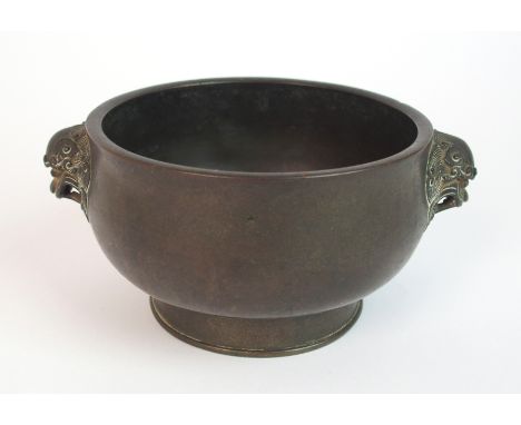 A Chinese bronze two handled censer the bowl cast with grotesque animal heads above a raised foot and six figure reign mark, 