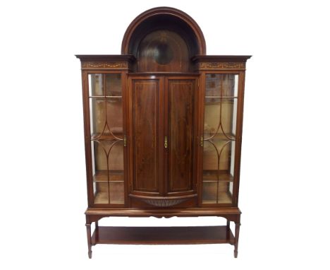 An Edwardian mahogany inlaid display cabinet on stand the arched top above a ribbon tied harebell panel above a pair of bowfr