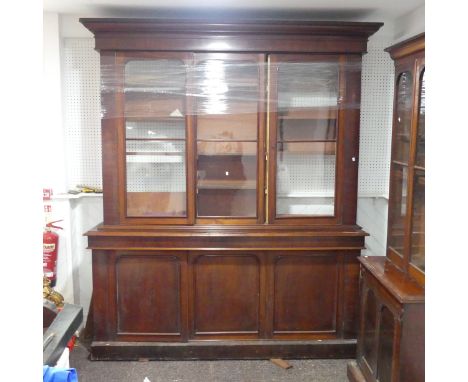 A large Victorian mahogany glazed Bookcase, overhanging moulded cornice above three large glazed cupboard doors, central bein