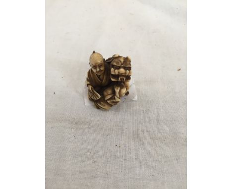 A Meiji period ivory netsuke of seated child and puppeteer with shi shi and fan