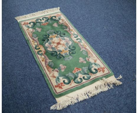 HEAVY QUALITY WASHED CHINESE RUG with embossed off-white and floral centre oval medallion and shaped border, on an emerald gr