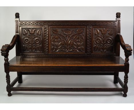 NINETEENTH CENTURY CARVED OAK SETTLE, the three panel back well carved with stylised foliage, flanked by mask capped downswep