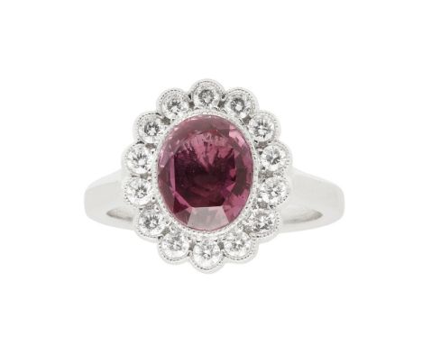 A ruby and diamond cluster ringmillegrain set with an oval cut ruby, in a single border of small round brilliant cut diamonds