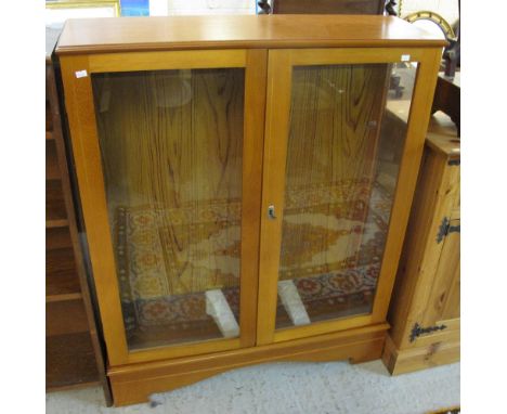 Modern beech two door display cabinet on bracket feet.