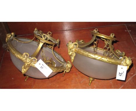 Pair of neoclassical design frosted glass ceiling light fittings with gilt metal frames, having rams head mounts. (2)