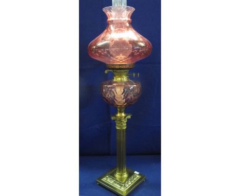 Brass corinthian double burner oil lamp with fluted cranberry glass reservoir and cranberry shade with clear chimney. 