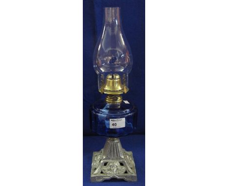 Early 20th Century brass single burner oil lamp with blue glass reservoir and cast metal base with clear chimney. 