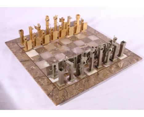 Modernist art metal chess set on marble board.