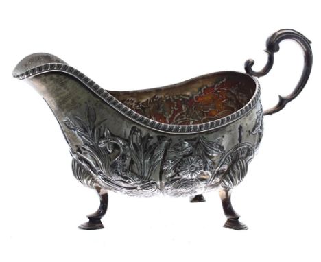 Late Victorian silver sauce boat, repousse decorated with wildlife, flowers and foliage, with C-scroll handle and raised on t