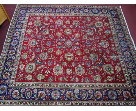 A Persian Tabriz carpet, having floral motifs on a rouge ground, within blue floral border, 332 x 310cm 