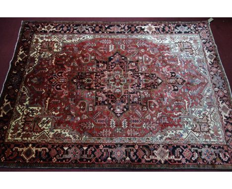 A Northwest Persian Heriz carpet, central diamond medallion with repeating petal motifs on a terracotta field, within stylise