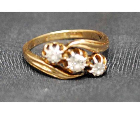 An 18ct gold three-stone diamond Cross Over Ring, the central stone approx 3.5mm diameter flanked by a pair of smaller stones