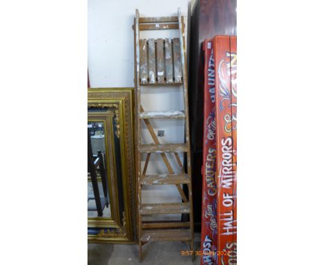 A set of vintage wooden stepladders and a tin trunk 