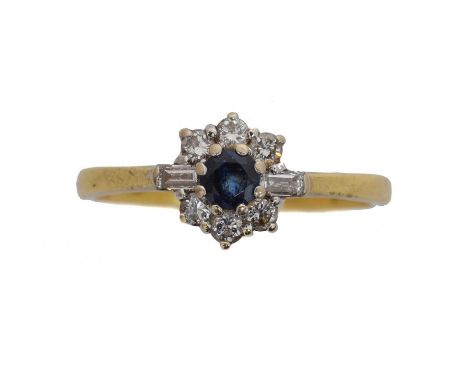 An 18ct gold sapphire and diamond cluster ring by Cropp & Farr. The circular shape sapphire within a brilliant and baguette c