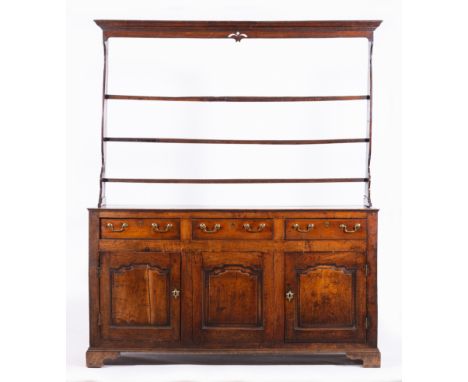 George III oak dresser,  three shelf delft rack with a moulded canopy, the base with three frieze drawers over three arched f