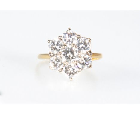 A diamond floral cluster ring, seven brilliant cut diamonds claw set in an 18 carat white gold mount, 1.8mm wide shank with s