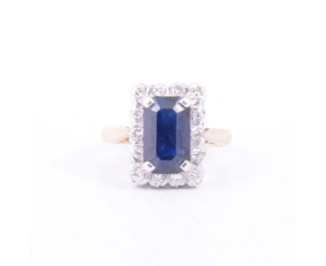 A sapphire and diamond rectangular cluster ring, a rectangular step cut sapphire 11.2mm x 6.4mm, claw set, surrounded by four