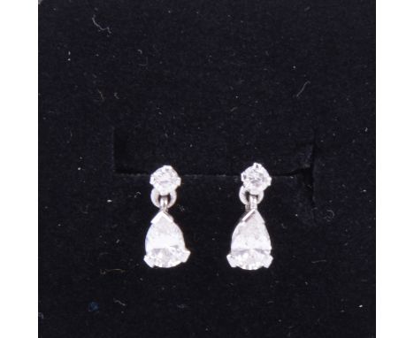 A pair of diamond earrings, a pear shaped diamond drop to each suspended from a small stud in all white metal mounts, pierced