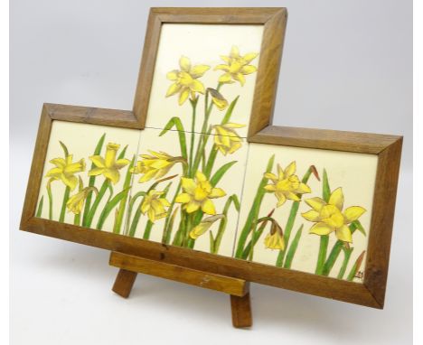 Set of four 19th/ early 20th century tiles painted with Daffodils signed DM, mounted as one in oak shaped frame, on easel, L5