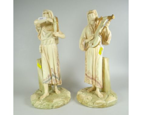 PAIR OF ROYAL WORCESTER BLUSHED IVORY EGYPTIAN REVIVAL FIGURES, modelled by JAMES HADLEY, each standing beside a plinth and p