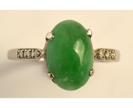 A platinum, jade and diamond ring, the oval cabochon jade set with tiny diamonds to the shoulders on simple shank, size P. CO