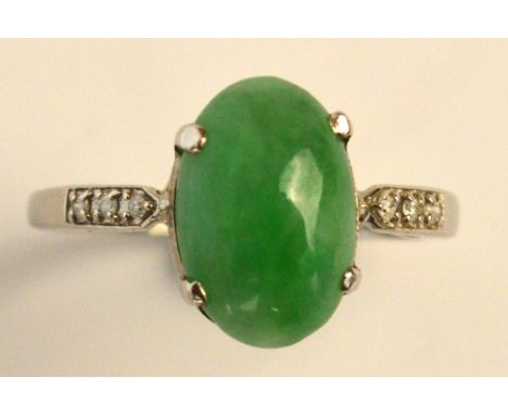 A platinum, jade and diamond ring, the oval cabochon jade set with tiny diamonds to the shoulders on simple shank, size P. CO