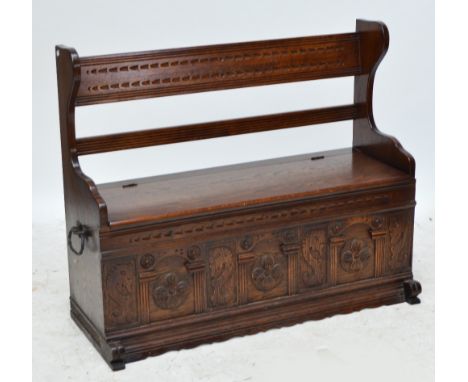A 1940s oak box seat hall bench with carved front panels.