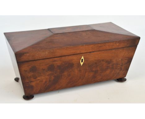 A large George mahogany sarcophagus shaped tea caddy, the hinged lid enclosing two lidded compartments and a central aperture