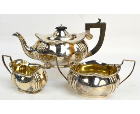 A George V hallmarked silver three piece tea service comprising an oval teapot with fluted decoration to the corners, length 