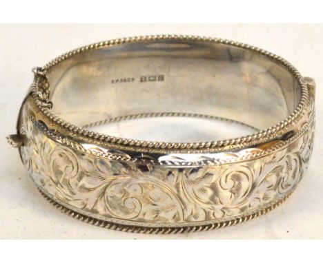 A hallmarked silver snap bangle engraved with foliate scrolls to one half, with security chain, Birmingham 1960, diameter 6cm