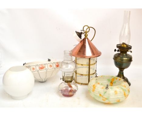 A brass oil lamp with funnel and glass globe shade, a further oil lamp with glass reservoir, a copper and brass ceiling light