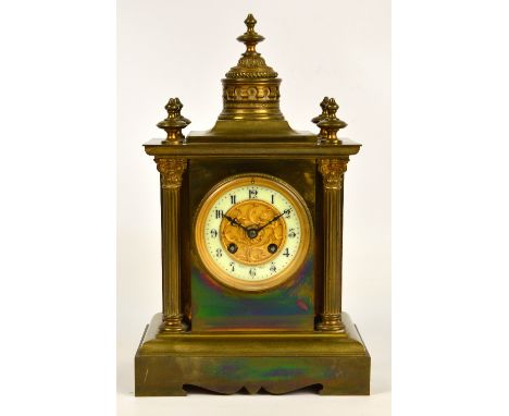 A late 19th century French brass cased mantel clock, the domed raised finial above circular dial set with Arabic numerals enc