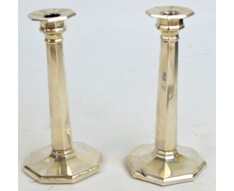 A pair of George V hallmarked silver Art Deco candlesticks, with octagonal tapering stems and spreading loaded bases, William