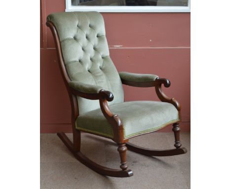 A Victorian mahogany framed rocking armchair with button upholstered padded back, padded arms, padded seat and ring turned fr
