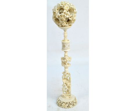 A large Chinese carved ivory puzzle ball on stand, the sectional stem decorated with architectural village landscape, height 