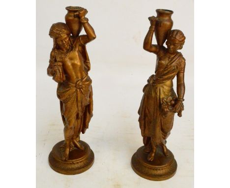 A pair of gilded metal figural lamp bases in the form of a male and female North African water carriers, on circular plinth, 