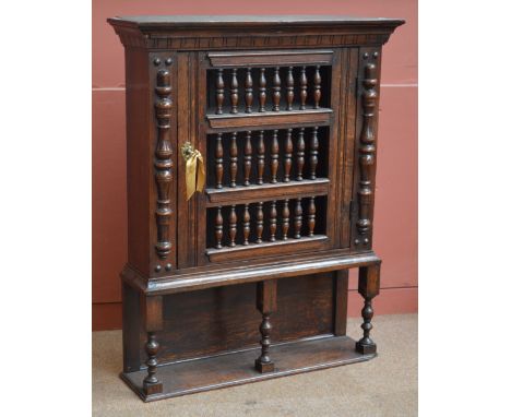 An oak food cupboard, the moulded cornice above a door set with three rows of open spindles raised on ring turned and block s