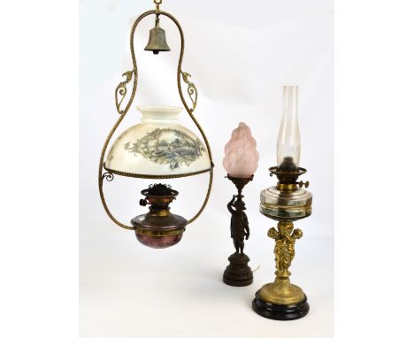 A Victorian oil lamp with figural brass central column and glass reservoir, a bronzed figural table lamp with frosted flaming