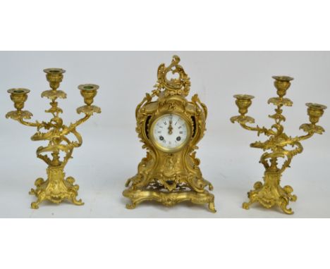 A 19th century French Rococo Revival clock garniture, the gilt clock decorated with rocailles, foliate scrolls and garlands o