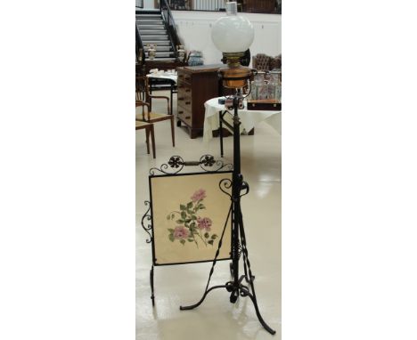 A wrought iron set of oil lamp and fire screen