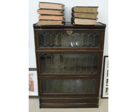 A three-tier oak leaded windowed Globe Wernicke bookcase (glass cracked to one section)