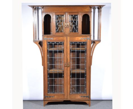 An Arts & Crafts cabinet, moulded cornice, above a plain frieze, leaded glazed doors enclosing shelves, flanked by open shelv