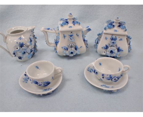 A DRESDEN MINIATURE PART TEA SET with moulded applied flowers painted in blue, (some chips to flowers, cover of jug missing)