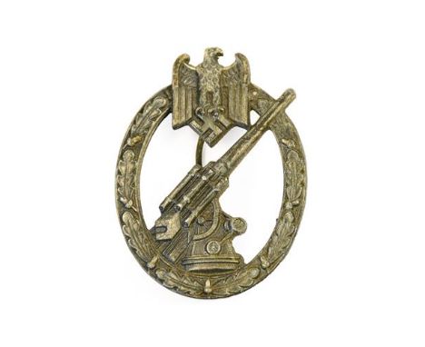A German Third Reich Army Flak Artillery Badge, in die cast white metal,  with vertical needle shape pin to the solid back, u