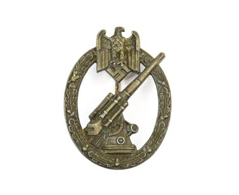 A German Third Reich Army Flak Artillery Badge, in die cast white metal,  with vertical needle shape pin to the solid back, u