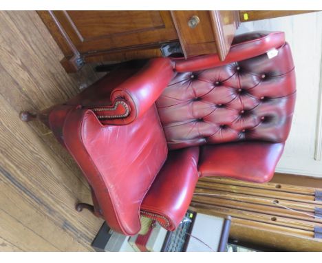 A red leather button back wing armchair