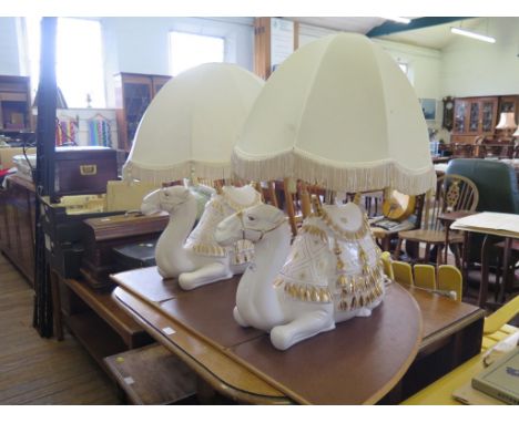 A pair of Spanish white ceramic and gilded table lamps, in the form of seated camels 31cm high (plus shades) (2)